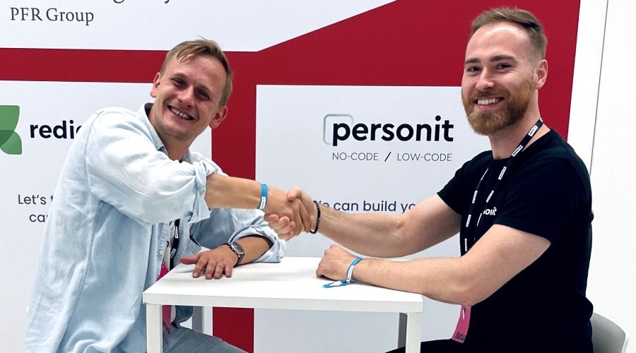 Personit booth with a no-code / low-code banner, the two founders shaking hands